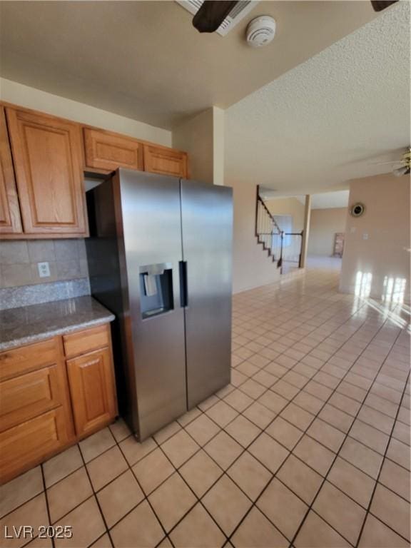 kitchen featuring stainless steel refrigerator with ice dispenser, ceiling fan, decorative backsplash, and light tile patterned floors