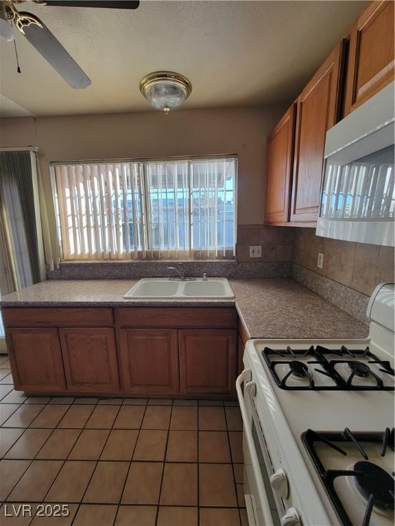 kitchen featuring a healthy amount of sunlight, sink, dark tile patterned flooring, and white appliances