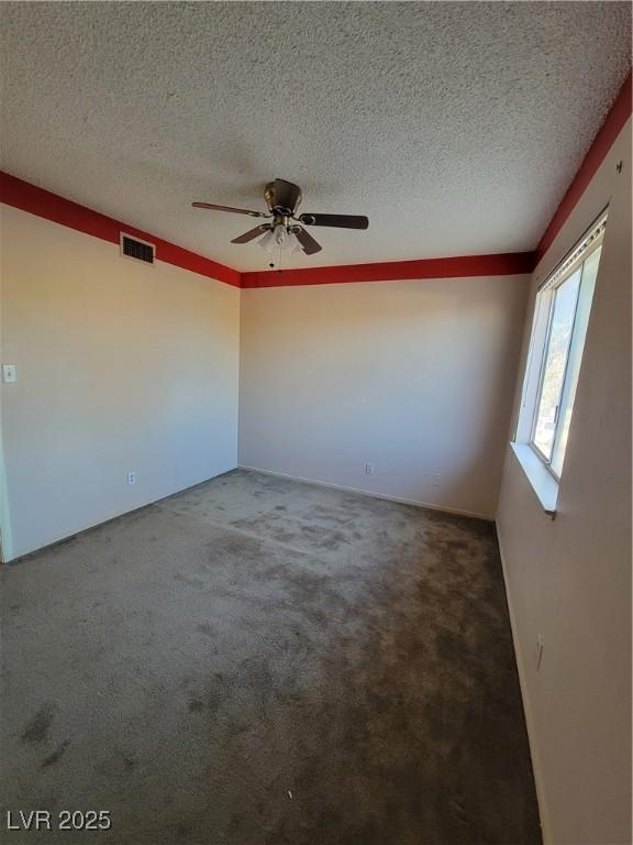 carpeted empty room featuring ceiling fan and a textured ceiling