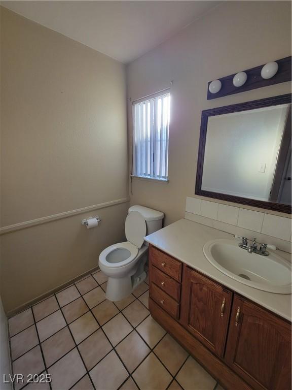 bathroom featuring tasteful backsplash, vanity, tile patterned floors, and toilet