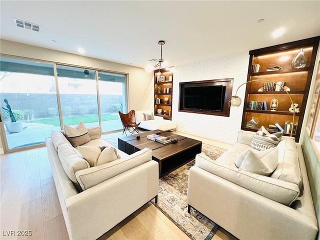 living room with brick wall and hardwood / wood-style floors