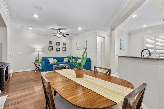 dining space with ceiling fan, ornamental molding, sink, and light hardwood / wood-style floors