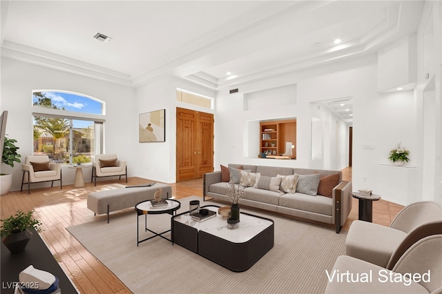 living room featuring a raised ceiling, light hardwood / wood-style floors, and a high ceiling