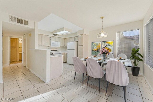 kitchen featuring white appliances, decorative light fixtures, and light tile patterned floors