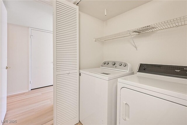 clothes washing area featuring washer and clothes dryer and light wood-type flooring