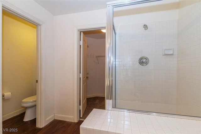 bathroom with hardwood / wood-style flooring, an enclosed shower, and toilet