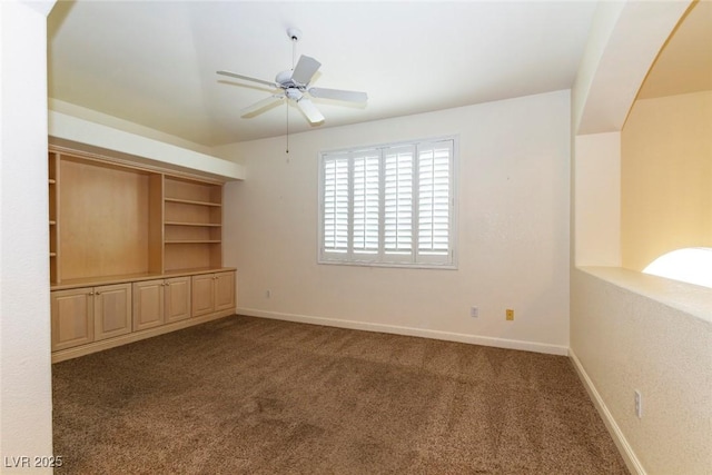 carpeted empty room featuring ceiling fan and built in shelves