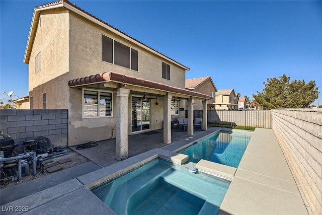 back of house with an in ground hot tub and a patio