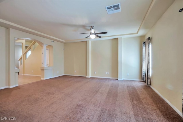 unfurnished room with ceiling fan, a raised ceiling, carpet floors, and ornate columns