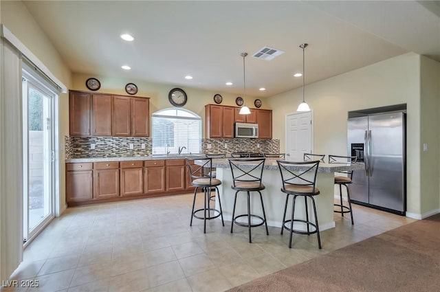 kitchen featuring pendant lighting, a breakfast bar, appliances with stainless steel finishes, a kitchen island, and light tile patterned flooring