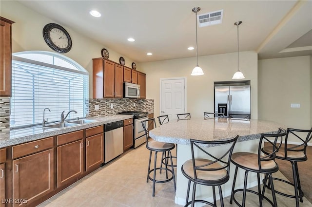 kitchen featuring sink, a breakfast bar area, appliances with stainless steel finishes, backsplash, and hanging light fixtures