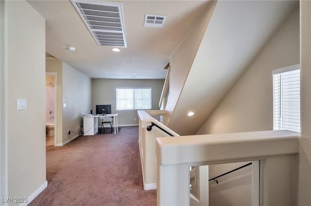 corridor with vaulted ceiling and dark colored carpet