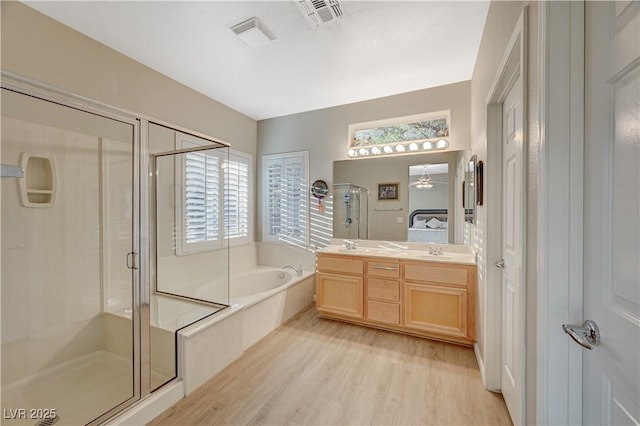 bathroom with ceiling fan, wood-type flooring, shower with separate bathtub, and vanity