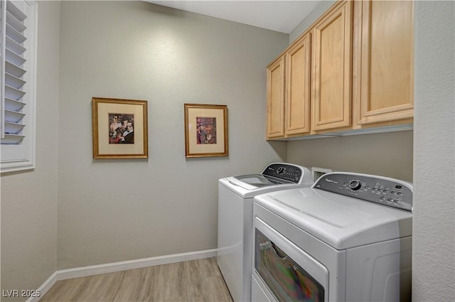 clothes washing area featuring cabinets, washer and dryer, and light hardwood / wood-style floors