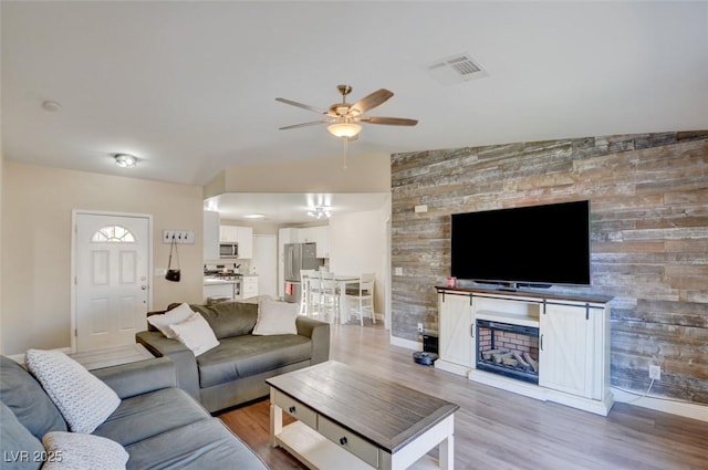 living room with lofted ceiling, hardwood / wood-style flooring, and ceiling fan