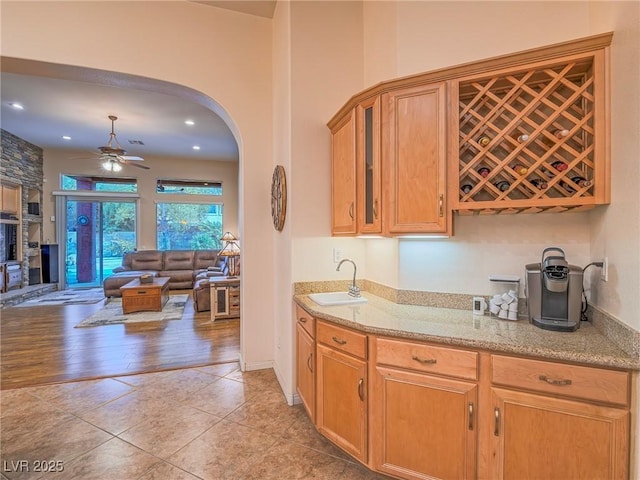 kitchen with light stone counters, ceiling fan, sink, and light tile patterned floors