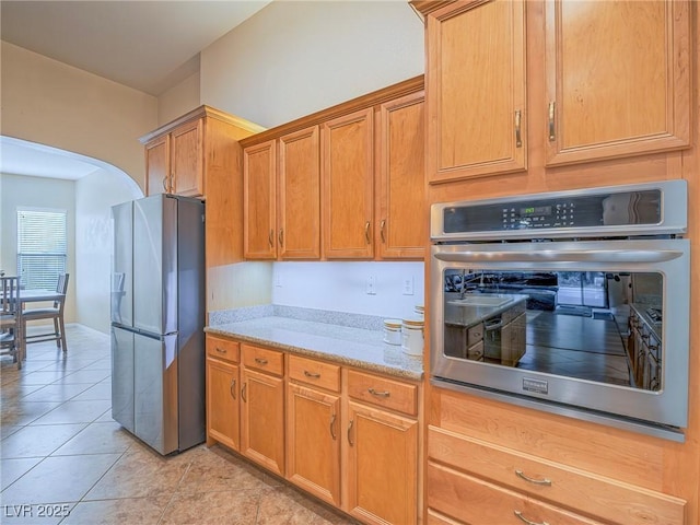 kitchen featuring light stone countertops, appliances with stainless steel finishes, and light tile patterned floors