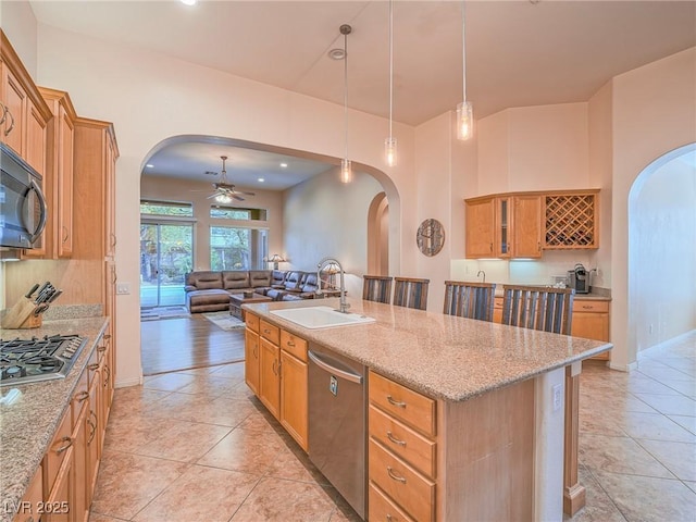 kitchen with a breakfast bar, pendant lighting, sink, stainless steel appliances, and a center island with sink