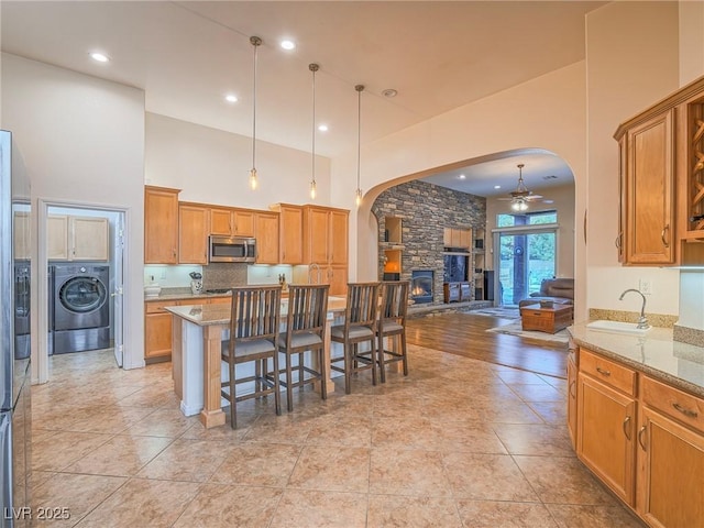 kitchen with washer / clothes dryer, decorative light fixtures, light stone countertops, and a kitchen bar