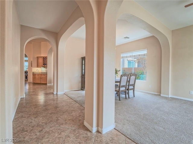 hall with sink and light colored carpet