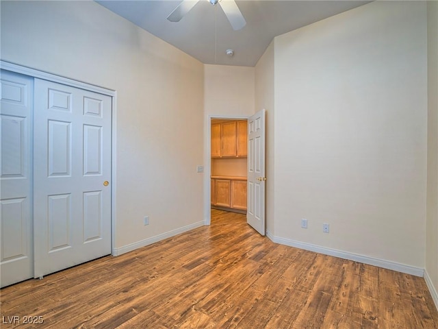 unfurnished bedroom featuring ceiling fan, wood-type flooring, and a closet