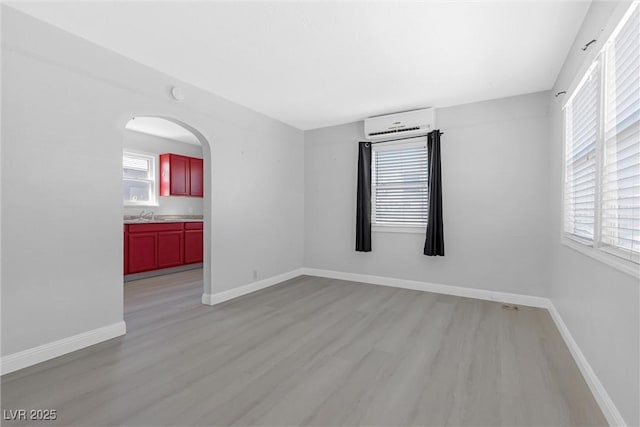 spare room featuring sink, light hardwood / wood-style flooring, and a wall unit AC