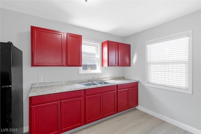 kitchen with black fridge, plenty of natural light, light hardwood / wood-style floors, and sink