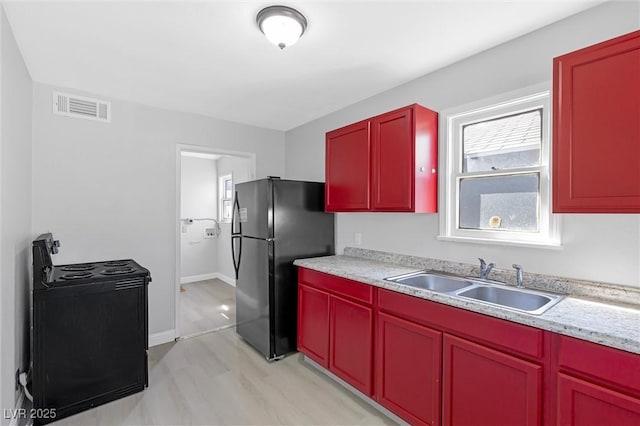 kitchen with sink, light hardwood / wood-style flooring, and black appliances