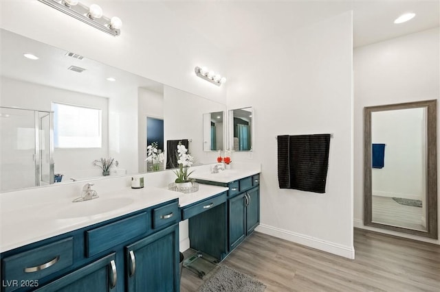 bathroom with hardwood / wood-style flooring, vanity, and a shower with shower door