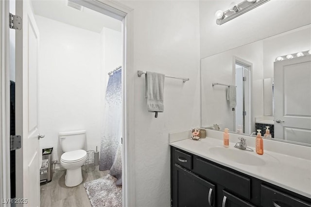 bathroom featuring vanity, wood-type flooring, and toilet