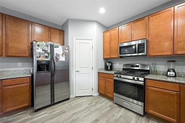 kitchen featuring light stone counters, light hardwood / wood-style flooring, and appliances with stainless steel finishes