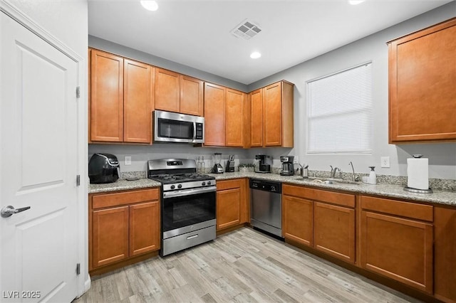 kitchen featuring sink, light hardwood / wood-style floors, light stone countertops, and appliances with stainless steel finishes