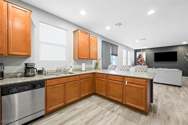 kitchen featuring sink, light stone counters, light hardwood / wood-style floors, stainless steel dishwasher, and kitchen peninsula