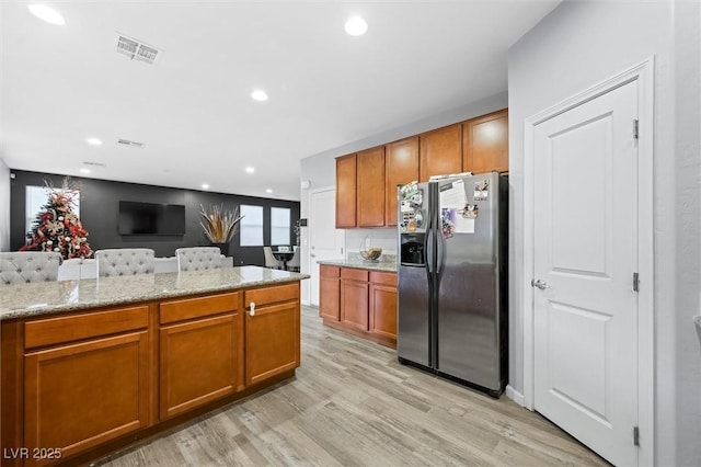 kitchen featuring stainless steel refrigerator with ice dispenser, light stone countertops, and light hardwood / wood-style floors