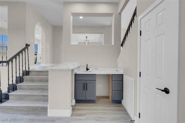 bar with gray cabinetry, sink, and light hardwood / wood-style floors