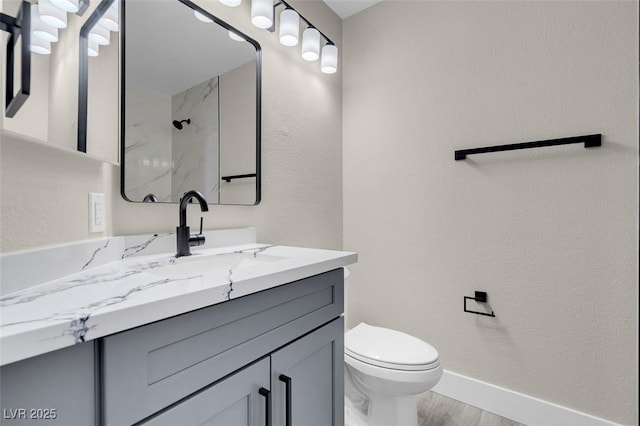 bathroom featuring vanity, tiled shower, and toilet