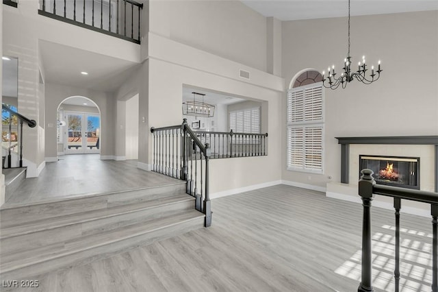 entryway with wood-type flooring, a towering ceiling, and an inviting chandelier