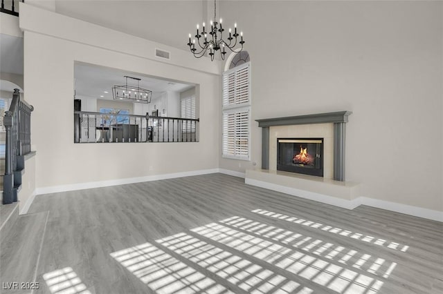 unfurnished living room featuring a tiled fireplace, wood-type flooring, and a chandelier