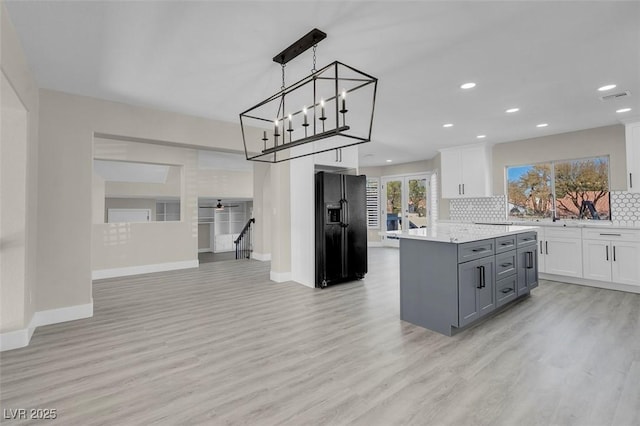 kitchen with white cabinetry, hanging light fixtures, gray cabinetry, a kitchen island, and black fridge with ice dispenser