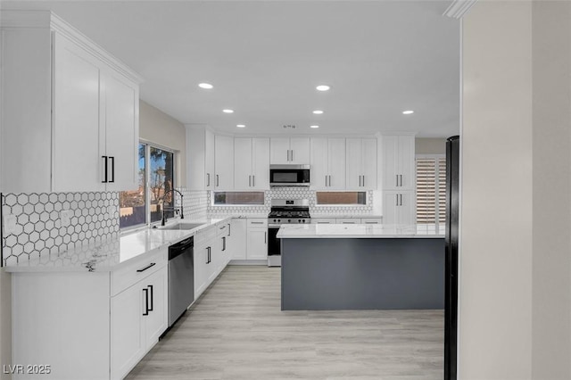 kitchen with sink, tasteful backsplash, light hardwood / wood-style flooring, appliances with stainless steel finishes, and white cabinets