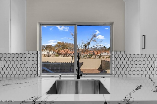 details featuring tasteful backsplash, light stone countertops, and sink