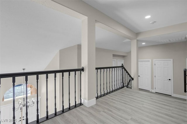 corridor with an inviting chandelier and light hardwood / wood-style flooring