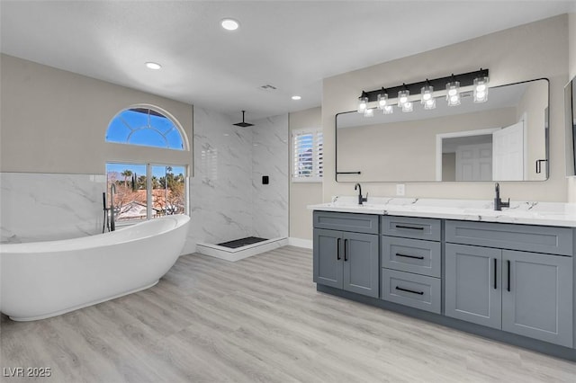 bathroom with vanity, hardwood / wood-style floors, shower with separate bathtub, and tile walls