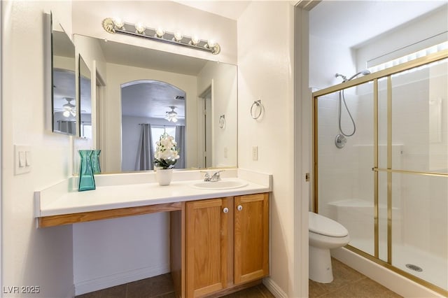 bathroom with walk in shower, tile patterned floors, toilet, vanity, and ceiling fan