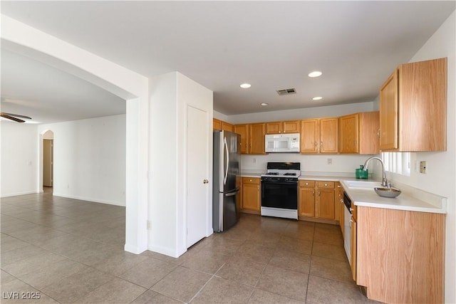 kitchen featuring stainless steel refrigerator, ceiling fan, sink, and stove