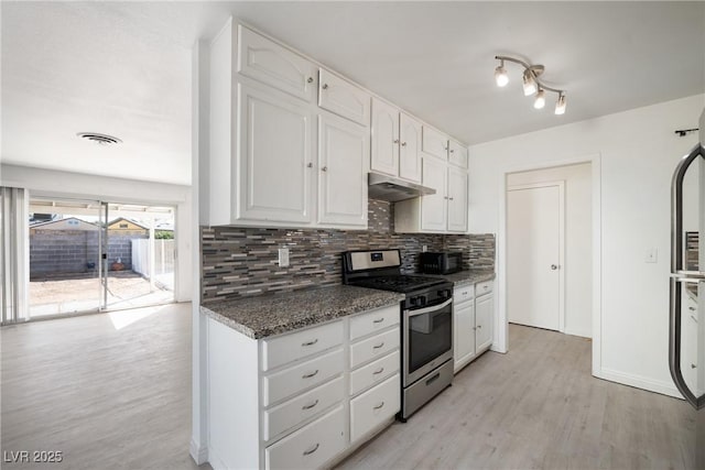 kitchen featuring dark stone countertops, white cabinets, decorative backsplash, stainless steel range with gas stovetop, and light wood-type flooring