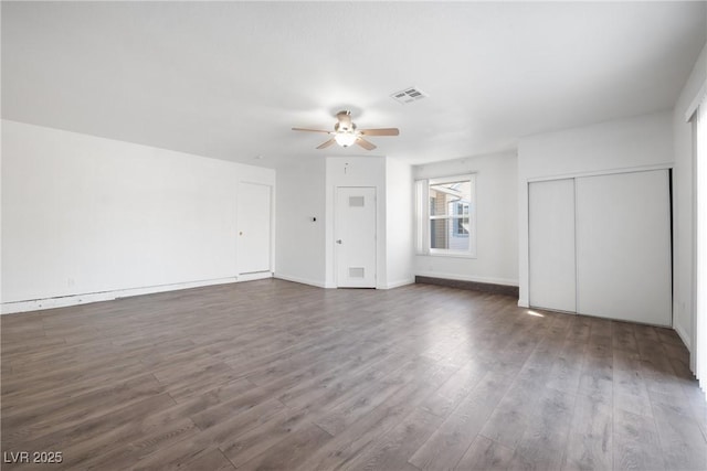 unfurnished living room featuring dark wood-type flooring and ceiling fan