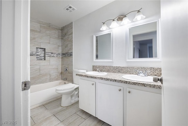 full bathroom with vanity, toilet, and tiled shower / bath combo