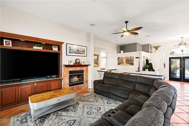 tiled living room with a tiled fireplace, ceiling fan, and french doors