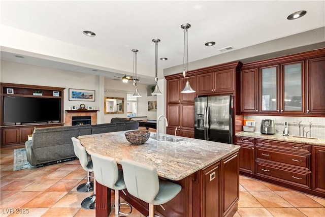 kitchen featuring a kitchen breakfast bar, sink, a kitchen island with sink, and stainless steel fridge with ice dispenser